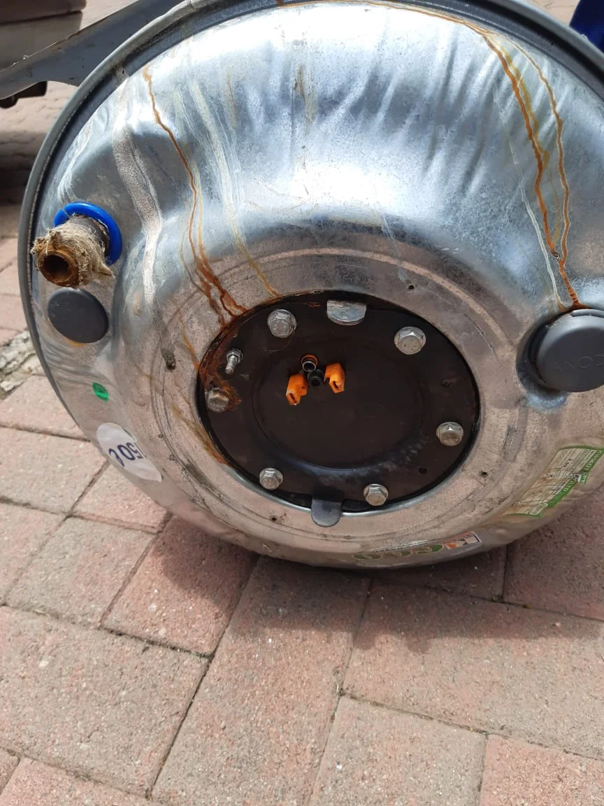 Burst geyser cylinder removed and prepared for replacement after visible rust and leakage.